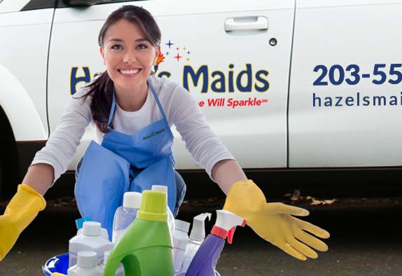 woman with yellow gloves and cleaning supplies in front of hazels maids van